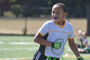 Young athlete wearing a blue protective mouthguard while playing sports outdoors